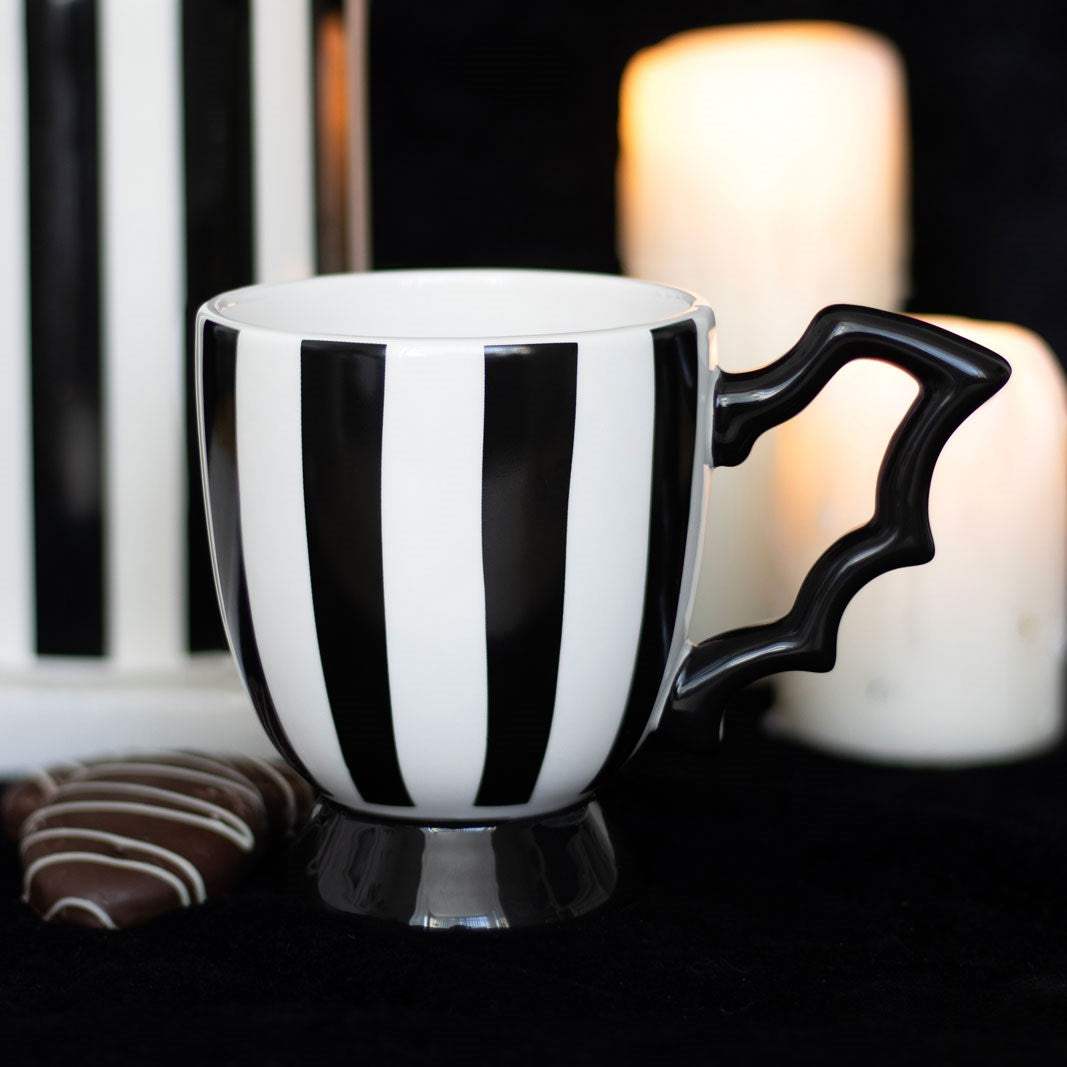 Black and white striped mug with a black handle on a dark background