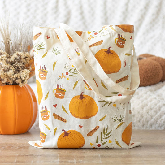 Tote bag with autumn-themed design featuring pumpkins and leaves on a wooden surface.