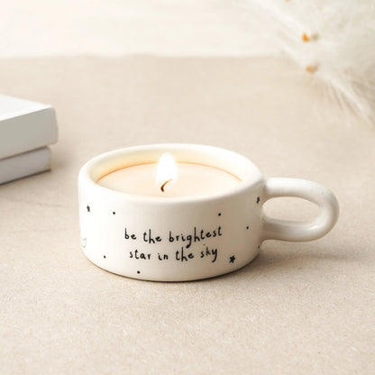 White candle holder with text 'be the brightest star in the sky' on a light surface.