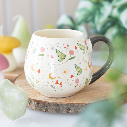 Decorative mug with moon, butterfly and flowers design on a wooden surface