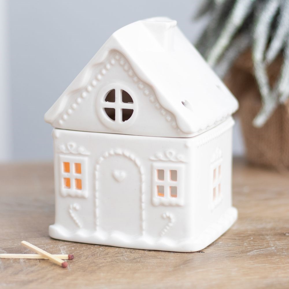 White ceramic house-shaped oil burner on a wooden surface