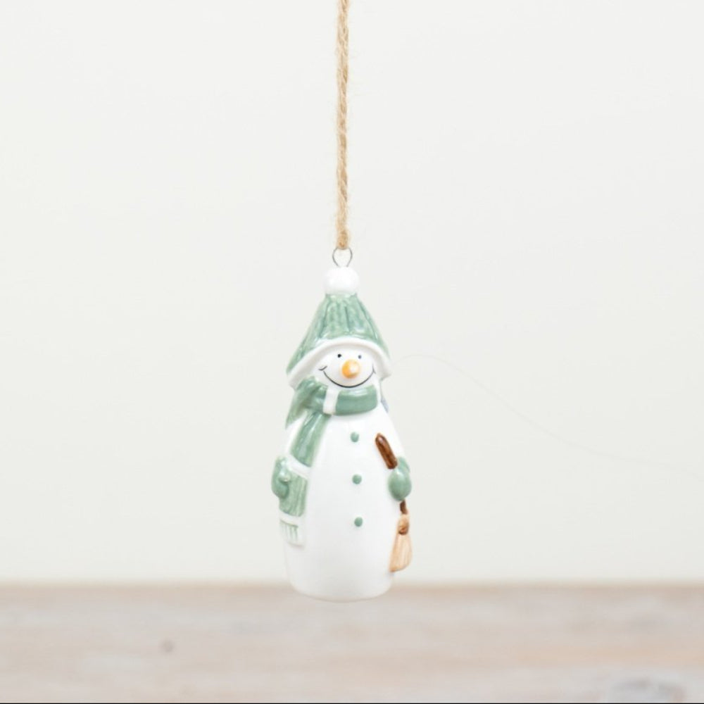 Decorative snowman ornament with a green scarf hanging on a white background
