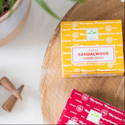 Box of Sandalwood dhoop incense cones to be used in a incense cone holder on a wooden surface.