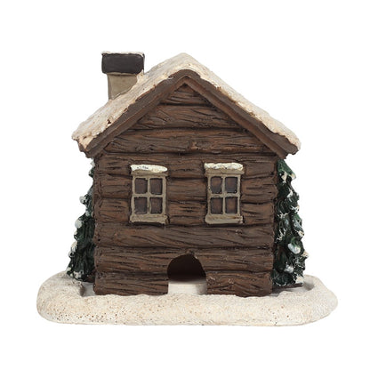 Dark brown log cabin incense cone holder, with snow on the roof and trees on the side.