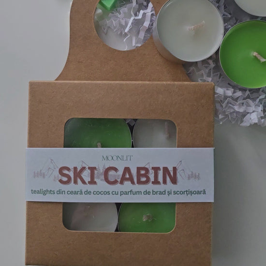 Ski cabin tealight candles packed in a cardboard box. Candles are green and white.