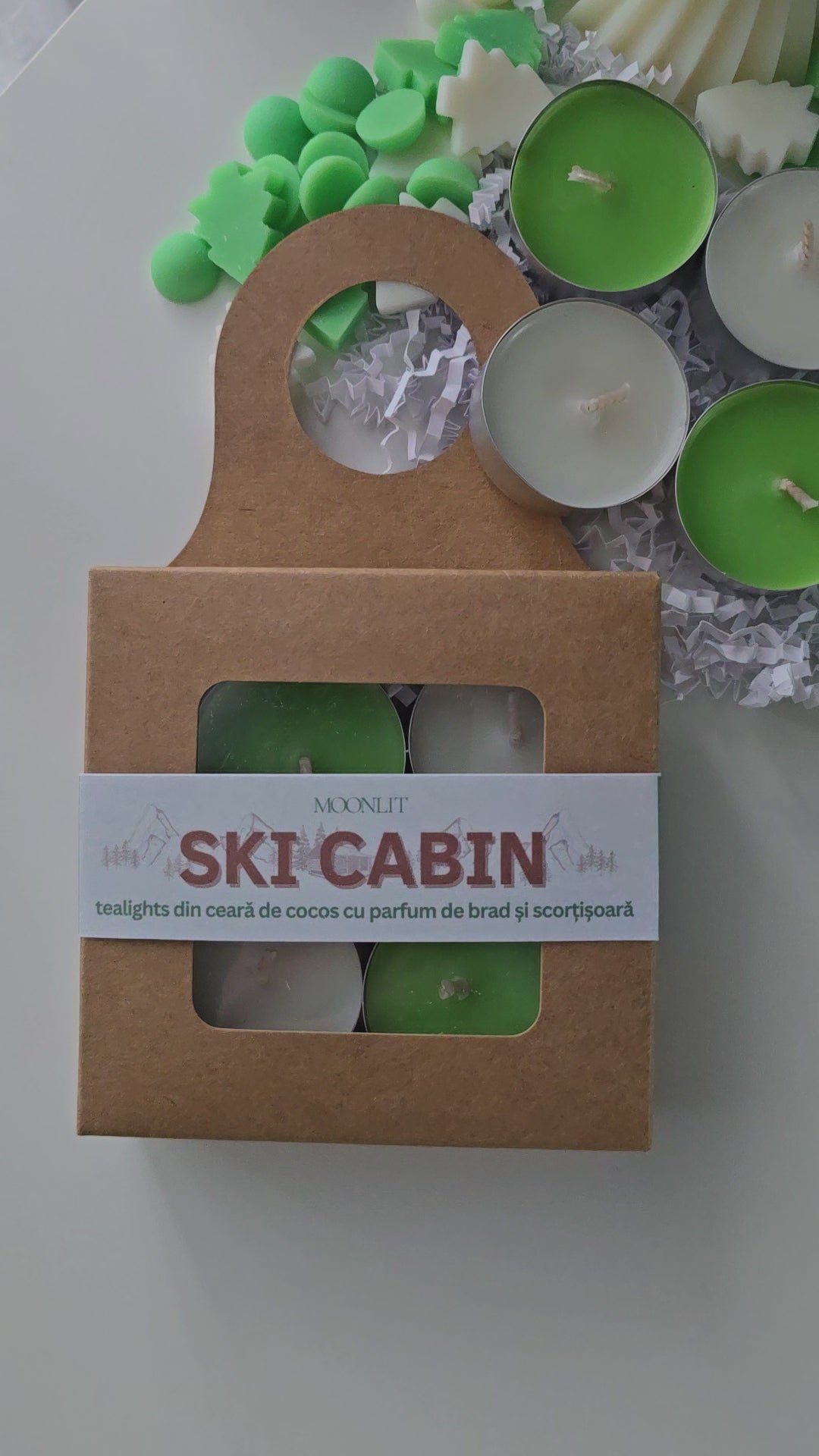 Ski cabin tealight candles packed in a cardboard box. Candles are green and white.