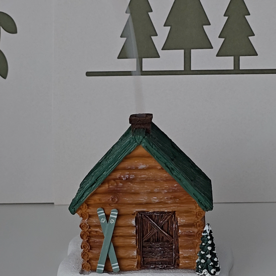 Ski Cabin incense burner shaped as a cabin in the woods with skies near the door.