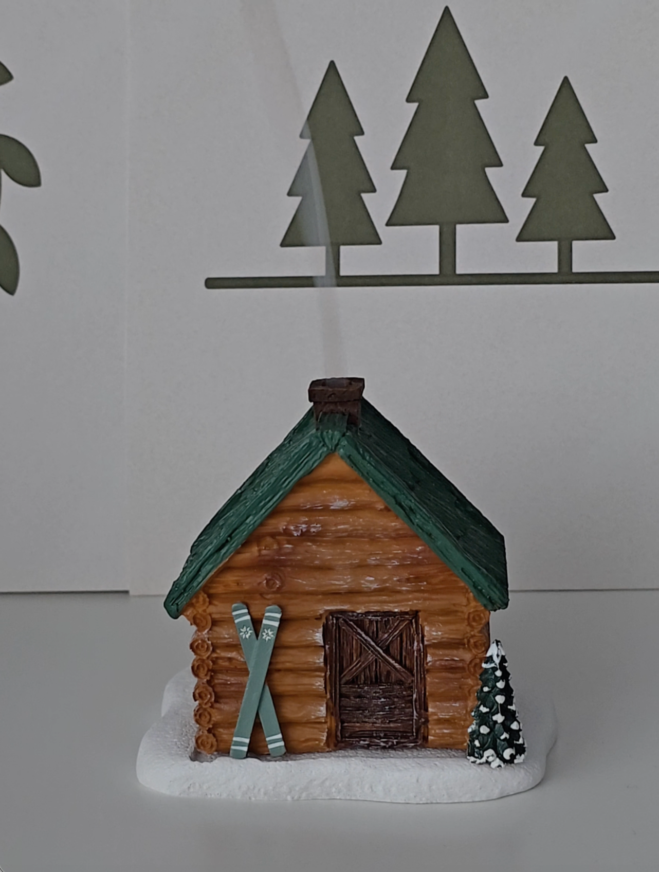 Ski Cabin incense burner shaped as a cabin in the woods with skies near the door.