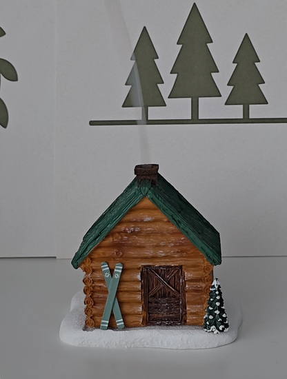 Ski Cabin incense burner shaped as a cabin in the woods with skies near the door.
