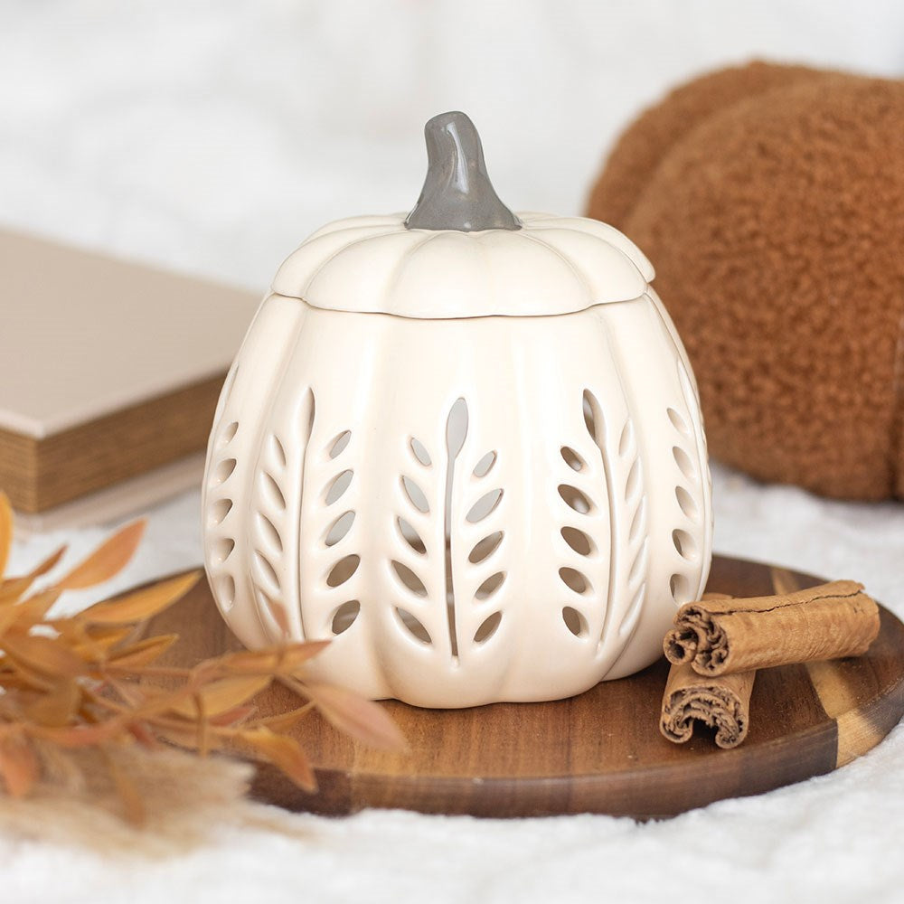 Cream Pumpkin Oil Burner – Leaf Cut-Out Design - White ceramic pumpkin-shaped lantern with cut-out designs on a wooden surface with leaves.