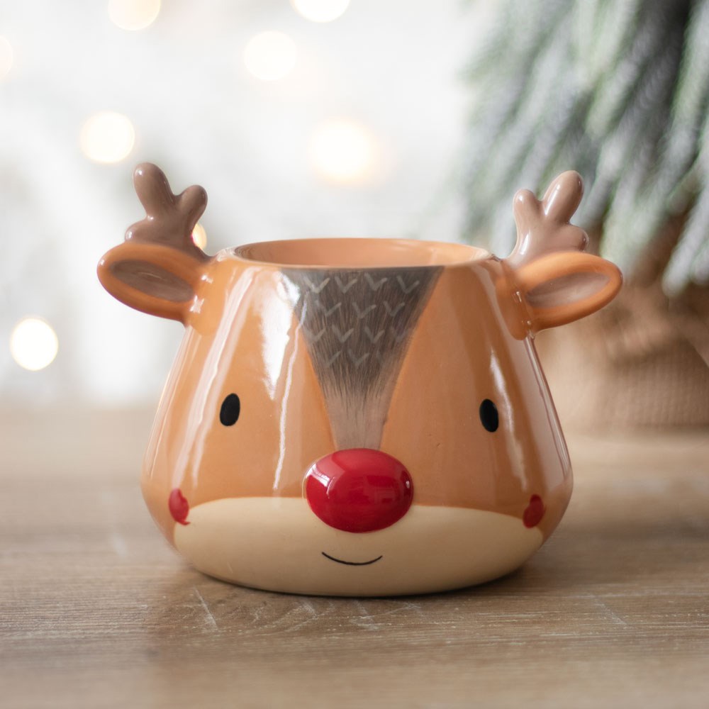 Reindeer-shaped oil burner with a red nose on a wooden surface with a blurred background