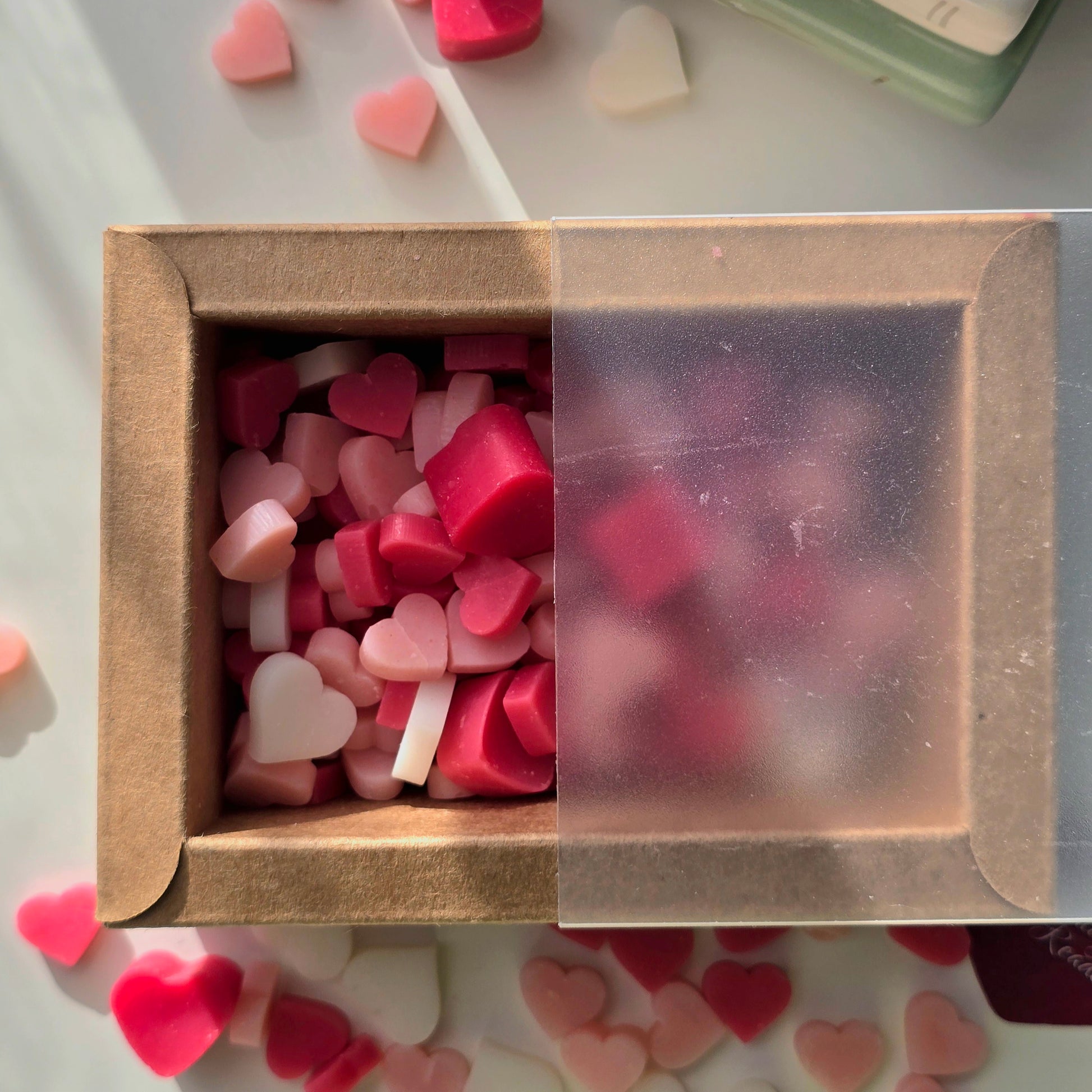 Box of heart-shaped wax melts, surrounded by more colorful heart-shaped wax melts.