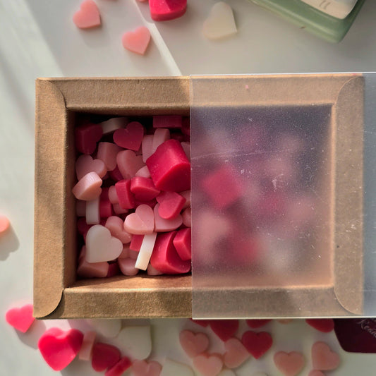 Box of heart-shaped wax melts, surrounded by more colorful heart-shaped wax melts.