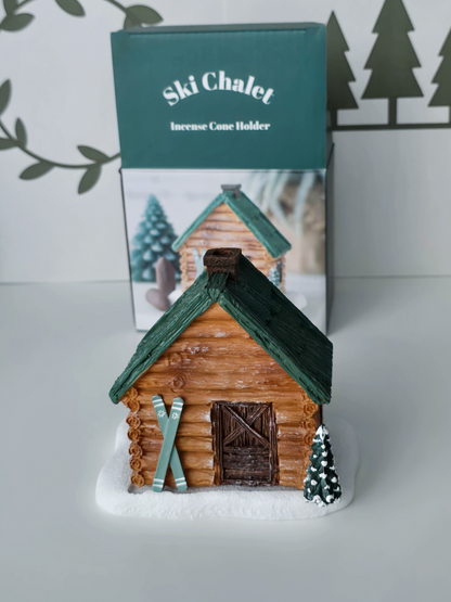 Wooden cabin-shaped incense holder with green roof on a white surface, branded 'Ski Chalet'.
