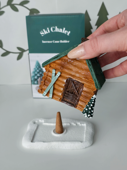 Ski chalet incense cone holder with a hand holding it above a white base.