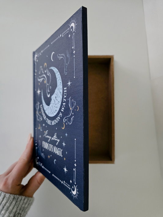Blue decorative box with celestial design held by a hand against a neutral background