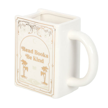 White coffee mug or tea cup with 'Read Books, Be Kind' text and palm golden trees. It can be used as bookish decor as well. Side view.